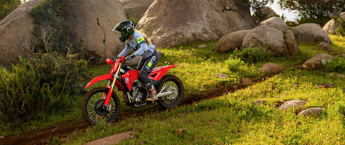 Honda CRF250RX dirt bike with off-road tires and sleek design, shown in a natural outdoor setting.
