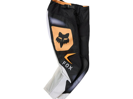Black and white FOX 180 Noble Youth MX pants with reinforced knees and adjustable waist for motocross riding.