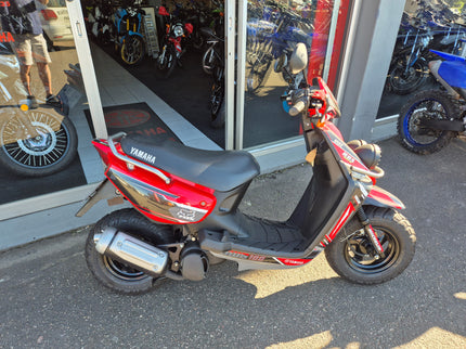 Used 2005 Yamaha BWS 100 scooter with black body and silver accents, parked outdoors on a paved surface.