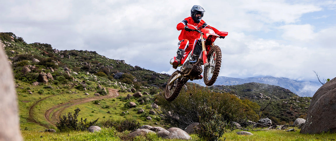 Honda CRF450X dirt bike with rugged off-road tires and sleek red and white bodywork, ready for trail riding.