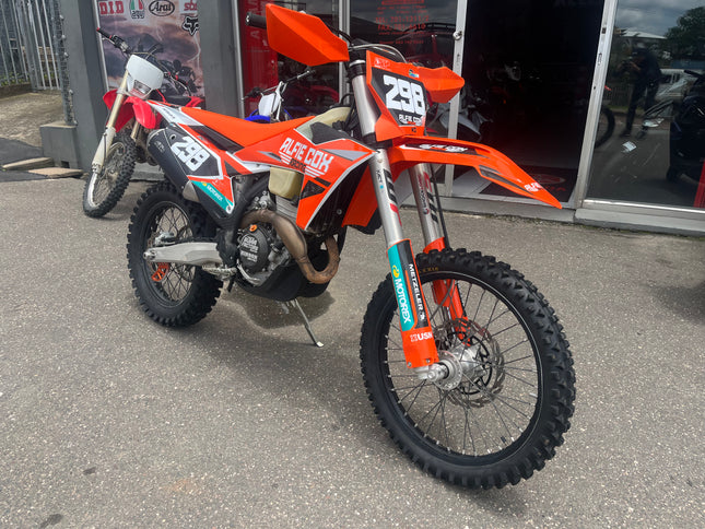 Used 2024 KTM 350 XCF dirt bike, orange frame and knobby tires, showcased on a trail with a clear sky.