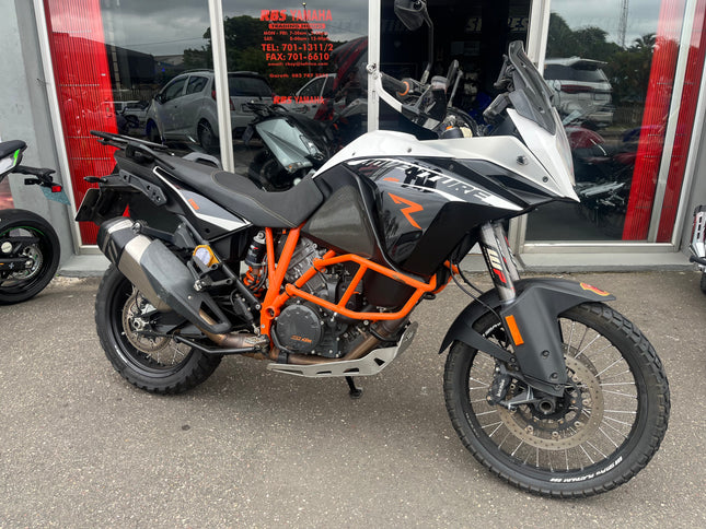 Used 2013 KTM 1190 Adventure R motorcycle with rugged design and off-road tires, parked on a scenic trail.