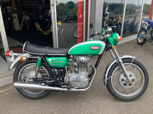 Yamaha 1970 XS 650 motorcycle with chrome details and classic design, parked outdoors with a clear view of the bike's side profile.