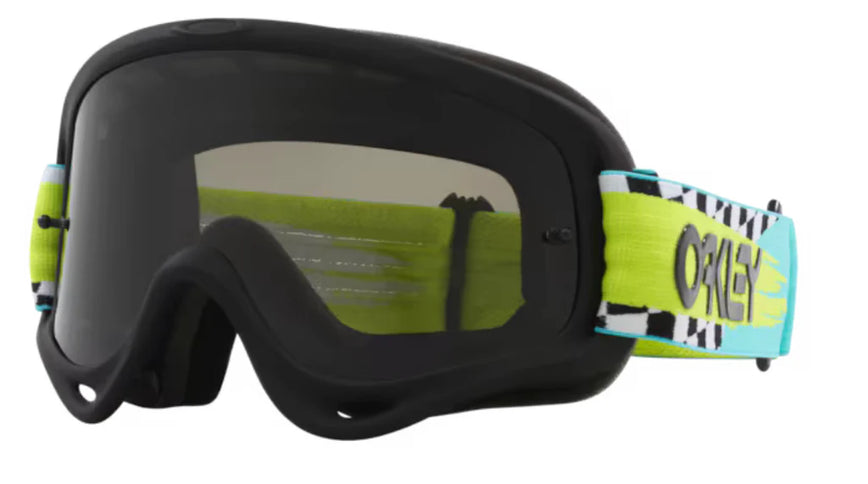 Oakley O-Frame MX Goggle with teal checkered frame and dark tinted lenses, designed for motocross riding.