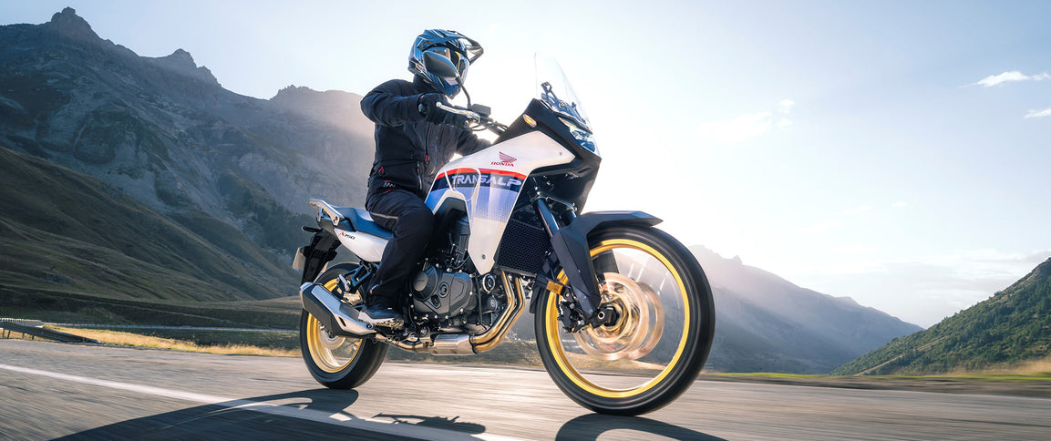 Honda TransAlp motorcycle parked outdoors, showcasing its sporty design and rugged build in a natural setting.